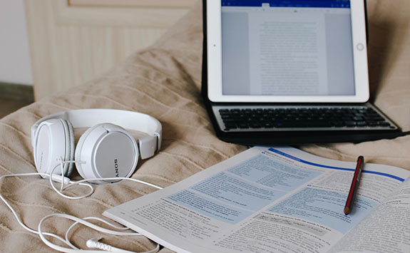 Tablet, book and headphones on a bed